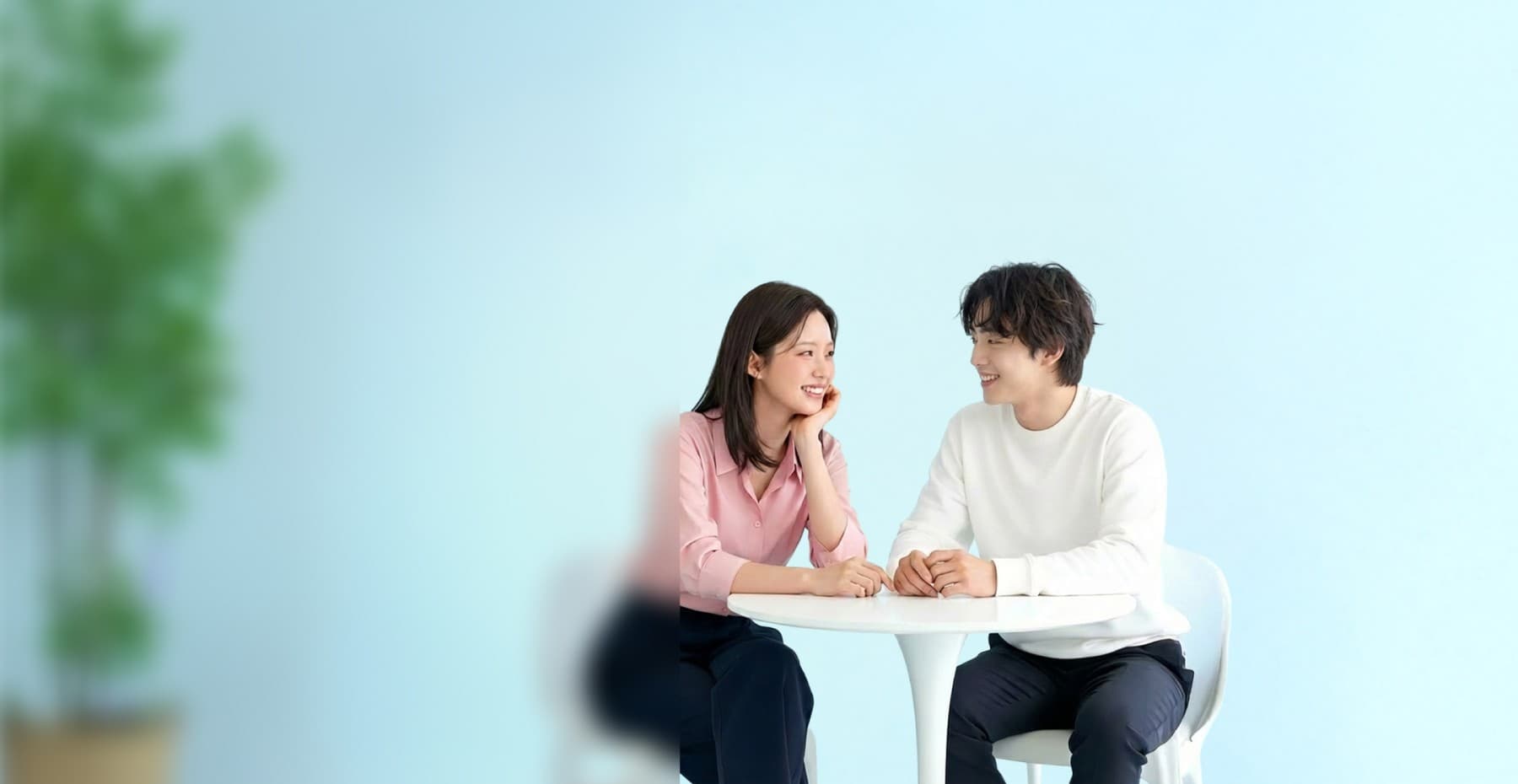하얀 테이블에 마주 앉아 서로를 바라보며 웃는 커플
